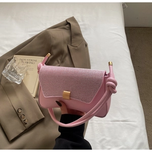 Detailed close-up of pink baguette bag showing glitter texture flap and gold lock detail