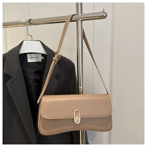 Close-up of khaki faux leather baguette bag with golden buckle on a black blazer background