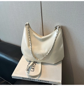 Close-up of cream crescent shoulder bag with metallic chain and smooth faux leather