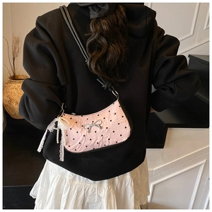 Detail of pink shoulder bag with black hearts, silver bow and lace pearl charm