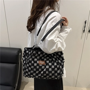 Chic checkerboard denim tote bag with frayed edges and leather chain strap shown on model