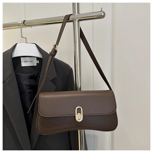 Detail of dark brown leather handbag with elegant oval gold buckle and adjustable strap