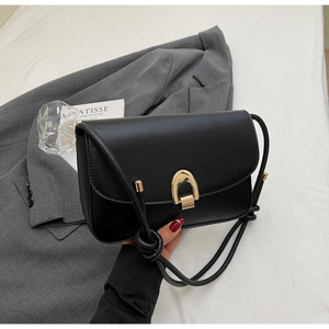 Detail of black leather square bag showing high-gloss gold buckle and fine stitching
