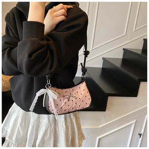 Detailed close-up of pink heart-print shoulder bag with silver bow and lace pearl charm