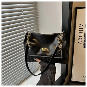 Detail der schwarzen Kunstledertasche mit Schlangenmuster und goldenen Beschlägen