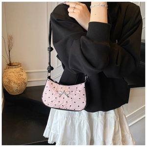 Detailed close-up of pink heart-patterned shoulder bag with silver bow and pleated texture