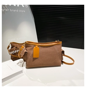 Detail of brown canvas shoulder bag showing twill texture and leather adjustable strap