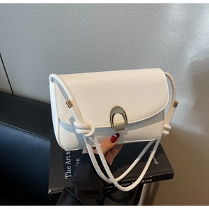 Close-up of white leather shoulder bag featuring a gold U-shaped metal lock and woven strap