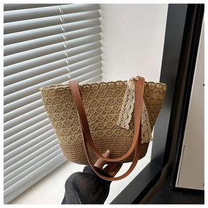 Détail du sac cabas en paille tissé à la main avec motifs et nœud en dentelle chic