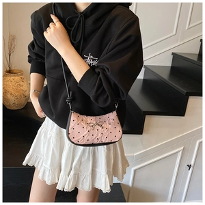 Detail of pink silk shoulder bag featuring black heart prints and silver bow accent