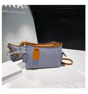 Detail of blue textured tote bag with brown leather trim and side pocket design