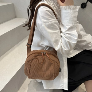 Brown corduroy crossbody bag with adjustable strap worn by model in a minimal setting