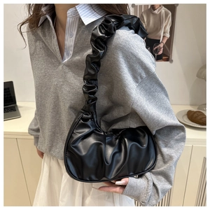Close-up of black ruched pleated underarm bag in soft PU leather on female model
