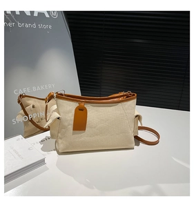 Detail of minimalist canvas tote with brown leather trim and decorative side pocket