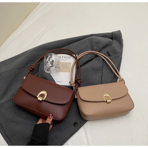Detailed view of brown and beige leather underarm bags with matte gold D-rings and knotted straps
