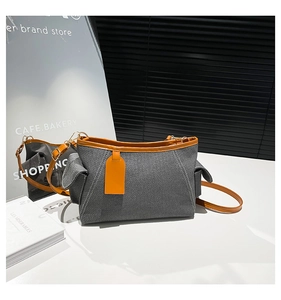Detail view of denim crossbody bag with brown leather trim and golden metal buckles