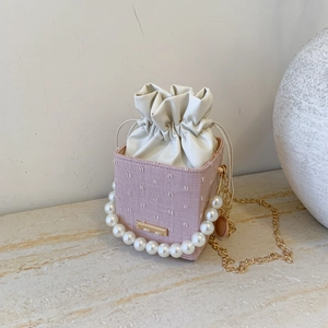 Detailed macro of pink textured mini bucket bag with pearl handle and golden chain