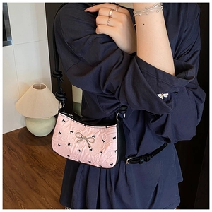 Close-up of pink pleated shoulder bag with black bows and silver metal buckle detail