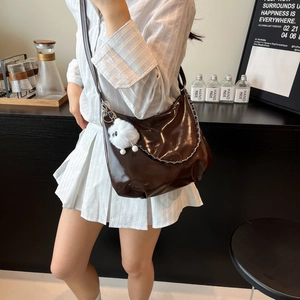Glossy dark brown shoulder bag with silver chain and plush dog charm on a model