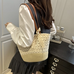 Sac cabas en paille avec bordure en dentelle blanche porté par un mannequin