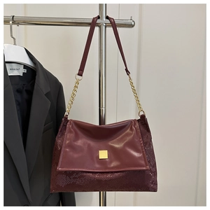 Detail of burgundy shoulder bag with snakeskin texture and golden square metal buckle