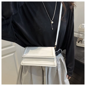 Detail of white quilted leather crossbody bag with elegant gold metal hardware on model