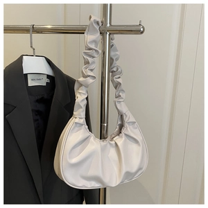 Close-up of ivory pleated cloud bag hanging on rack with elegant minimalist folds