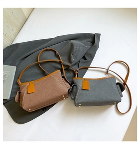 Detail view of canvas crossbody bags with leather trim and gold protective bottom rivets