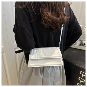 Rear view of model wearing a white quilted crossbody bag with sleek rectangle design