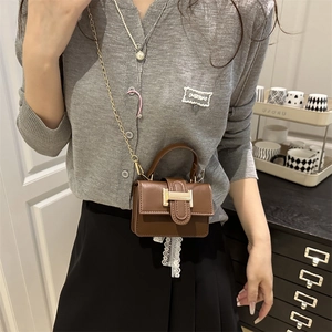 Mini borsa a mano minimalista marrone scuro con catena dorata in un interno casa