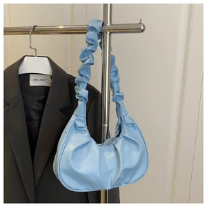 Close-up of light blue pleated hobo bag with a matching ruched handle on a hanger