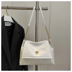 Close-up of white crossbody bag featuring gold metal buckle and snake-textured side panels