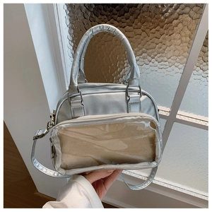 Silver metallic ita bag with clear PVC window and adjustable strap shown held in hand
