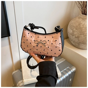 Detail showing pink pleated bag texture with heart prints and silver bow buckle