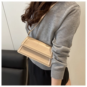 Detail of beige shoulder bag with horizontal padded texture and slim leather strap