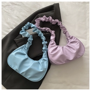 Detailed view of light blue and lavender pleated PU leather hobo bags on black fabric