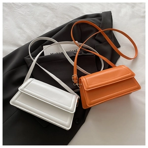 Detail of white and orange crossbody bags with leather texture and gold hardware details