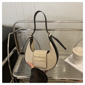 Detail of beige woven hobo bag with black leather trim and wave-shaped gold buckle
