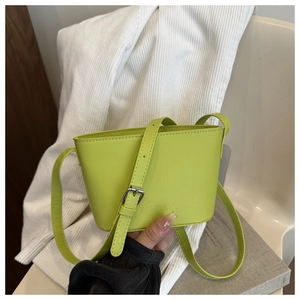 Detail of lime green leather bucket bag with embossed logo and adjustable strap