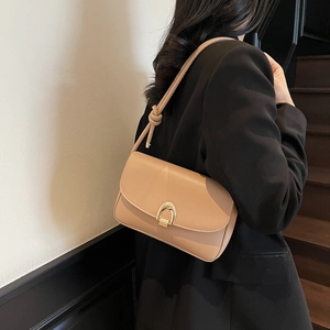 Minimalist beige shoulder bag with gold horseshoe buckle and knotted strap on model