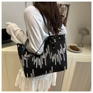 Detailed view of black tote bag featuring colorful zigzag wave embroidery on fabric