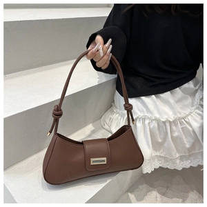 Detail view of brown faux leather baguette bag with gold buckle and knotted shoulder strap