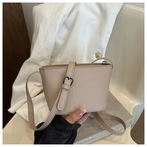 Detail view of beige faux leather bucket bag with silver buckle and embossed logo
