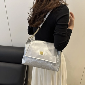 Silver snake pattern shoulder bag with gold logo and chain strap shown on model