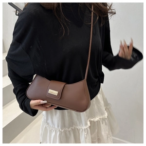 Detail of a brown leather shoulder bag with a sleek gold buckle and slim strap