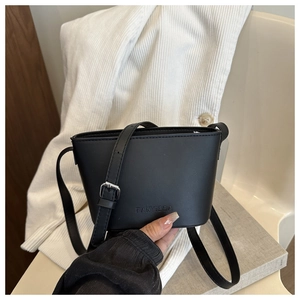 Detail of black leather bucket bag featuring debossed logo and silver buckle strap