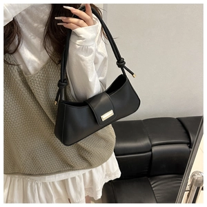 Detail of black faux leather bag with gold buckle and unique knotted strap handle