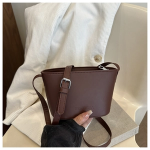Close-up of dark brown leather bucket bag showing embossed logo and matte texture