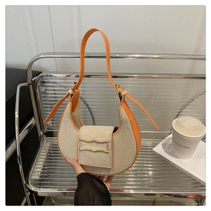 Detail of canvas crescent bag with orange leather trim on a minimalist metal bench