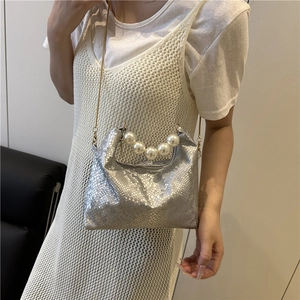 Silberne Umhängetasche mit Schlangenmuster, Perlengriff und goldener Kette am Model getragen